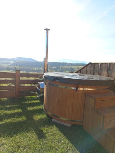 a wooden tub sitting in the grass next to a fence at Witówka in Grywałd