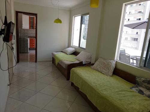 a room with two beds and a tv and windows at Apartamento cobertura em balneário Camboriú in Balneário Camboriú