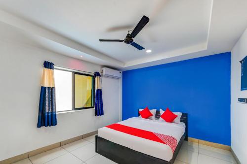 a bedroom with a blue wall and a bed with red pillows at SPOT ON Hotel Utrishree in Khandagiri
