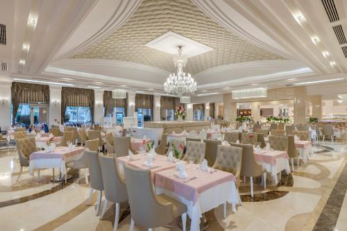 a banquet hall with tables and chairs and a chandelier at Dobedan Exclusive Hotel & Spa ''Ex Brand Alva Donna Exclusive Hotel & Spa'' in Belek