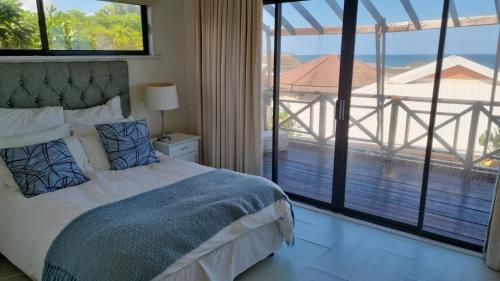 1 dormitorio con cama y vistas a un balcón en Kidds beach house, en Kiddʼs Beach
