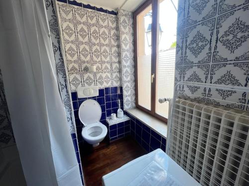 ein blau gefliestes Bad mit einem WC und einem Fenster in der Unterkunft L'atypique Briey Terrasse Un Séjour à Part in Briey