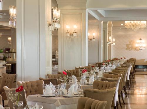a long dining room with white tables and chairs at Dobedan Exclusive Hotel & Spa ''Ex Brand Alva Donna Exclusive Hotel & Spa'' in Belek