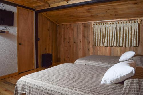 a bedroom with two beds and a television in it at Campestre DAARLU in Huauchinango