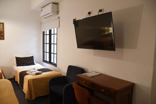 um quarto com uma cama e uma televisão na parede em Hotel Pueblo Huarpe em San Luis