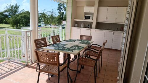 a patio with a table and chairs on a balcony at Appartements village Pierre et Vacances vue mer Aouara Roucou Malaka Guadeloupe St Anne in Sainte-Anne