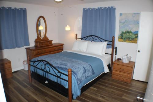 a bedroom with a bed and a mirror and blue curtains at Beautiful Ranch Home Between Virginia Beach and Norfolk in Virginia Beach