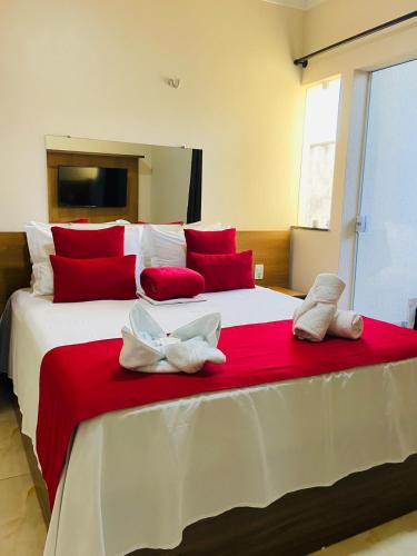 a large bed with red and white pillows on it at Hotel Camocim in Camocim