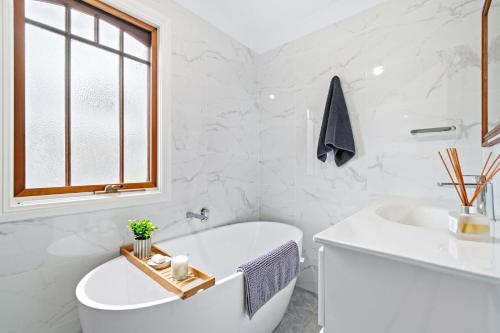 a white bathroom with a tub and a sink at Bells Rest with a view in Kurrajong