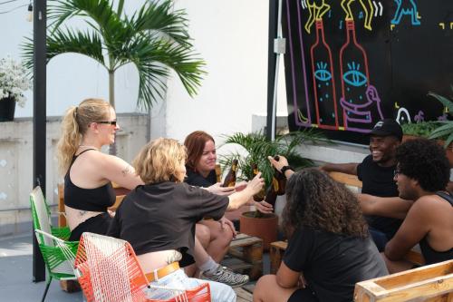 un grupo de personas sentadas alrededor de una mesa con bebidas en La Palmera Hostel, en Cali