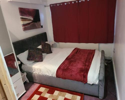 a small bedroom with a bed with a red curtain at Cosy1 bedroom,sleeps up to4guest in Hornchurch