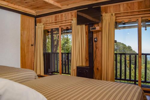 a bedroom with a bed and a balcony with windows at Campestre DAARLU in Huauchinango