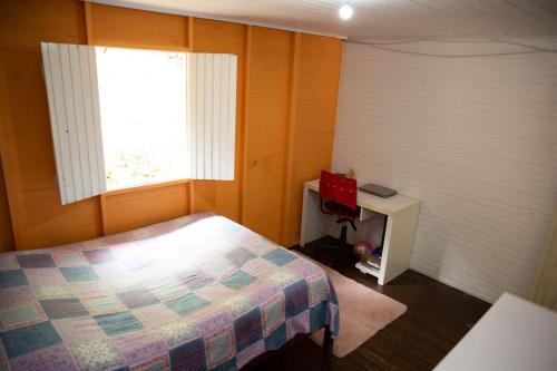 1 dormitorio con cama, ventana y escritorio en Casa de Campo com piscina em Marechal Floriano ES, en Marechal Floriano