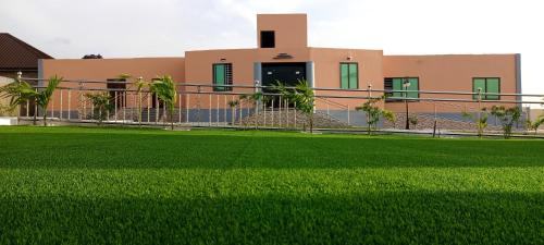 a house with a green lawn in front of it at Bella Ella Hotel & Event Center in Kasoa