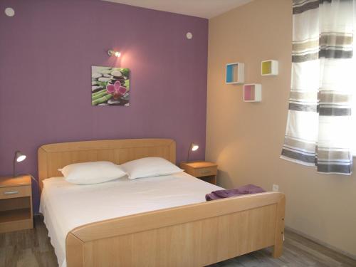 a bedroom with a bed and a purple wall at Apartments Rubinić in Jelsa