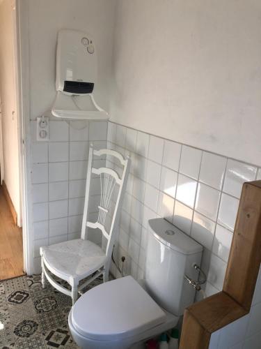 a bathroom with a toilet and a chair in it at Les Terrasses de la Montagne Noire. Pays Cathare in Cuxac-Cabardès