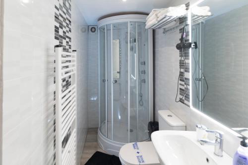 La salle de bains blanche est pourvue d'une douche et d'un lavabo. dans l'établissement Don Víctor, à Salamanque