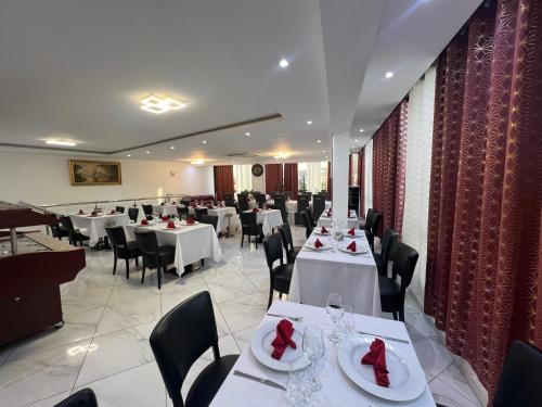 a dining room with white tables and black chairs at Residencial Santo Amaro in Tarrafal