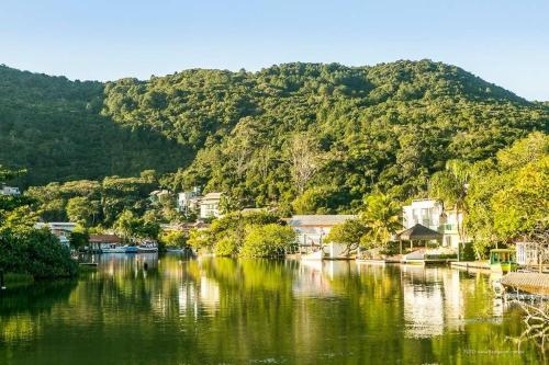 un río con casas, árboles y una montaña en Modernos chalés a 90 metros da praia, en Florianópolis