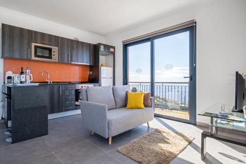 a kitchen and living room with a couch and a table at Vila Brava Cottage in Ribeira Brava