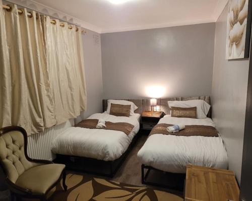 ein Schlafzimmer mit 2 Betten und einem Stuhl darin in der Unterkunft Sleek 2 bedroom flat-sleeps up to 5 guest in Hornchurch