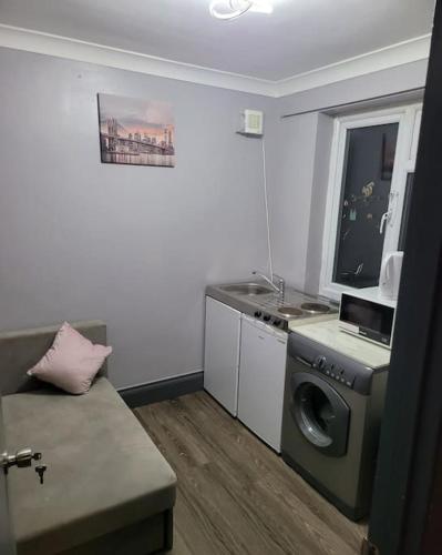 a living room with a washing machine and a window at Sleek 2 bedroom flat-sleeps up to 5 guest in Hornchurch