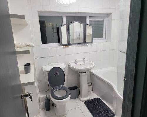 a white bathroom with a toilet and a sink at Sleek 2 bedroom flat-sleeps up to 5 guest in Hornchurch