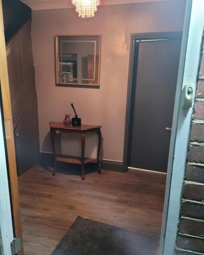 a hallway with a table and a mirror and a door at Sleek 2 bedroom flat-sleeps up to 5 guest in Hornchurch