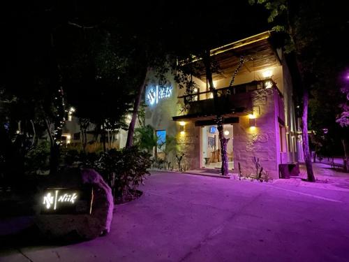 un bâtiment avec des lumières violettes sur une rue la nuit dans l'établissement Niik Tulum, à Tulum