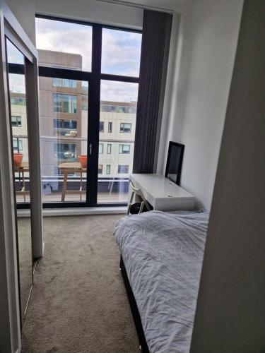 Habitación con cama, escritorio y ventana. en Stunning City View Apartment, en Londres