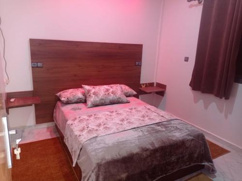 - une chambre avec un lit et une tête de lit en bois dans l'établissement Appartement luxueux à louer à Taounate, à Taounate