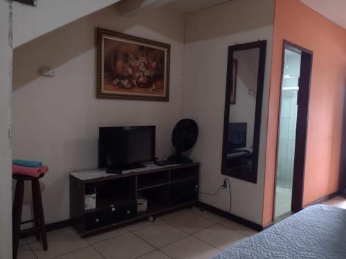 a bedroom with a tv and a mirror on the wall at Conforto e simplicidade! Casa top com garagem, cozinha, banheiro e quarto in Cabo Frio