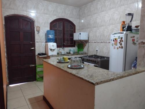 a kitchen with a counter top and a refrigerator at Conforto e simplicidade! Casa top com garagem, cozinha, banheiro e quarto in Cabo Frio
