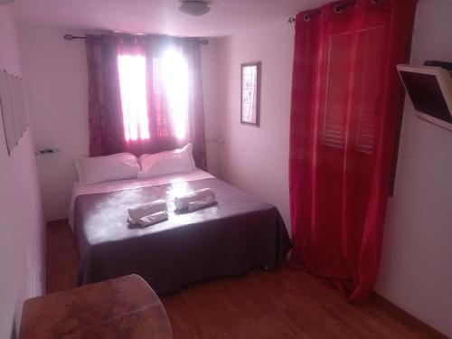 a small bedroom with a bed with red curtains at Appartamento con giardino Civitavecchia in Civitavecchia