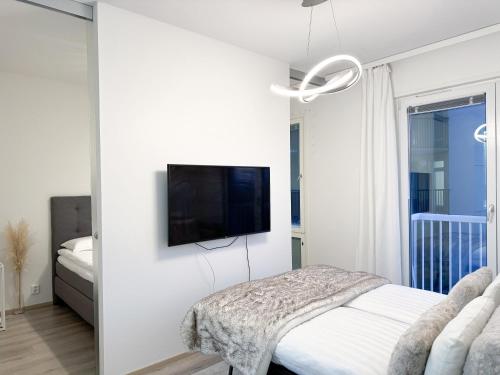 a white bedroom with a tv on a wall at Hostit Arctic Apartments in Rovaniemi