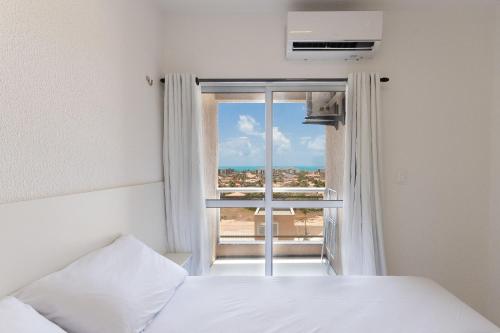a bedroom with a window with a view of the ocean at Beach Townhouses #C13 - Apartamento por Carpediem in Aquiraz