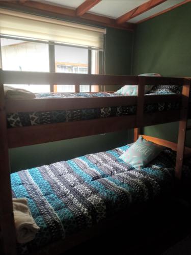 1 dormitorio con 2 literas y ventana en Cabaña Gesell, en Puerto Natales