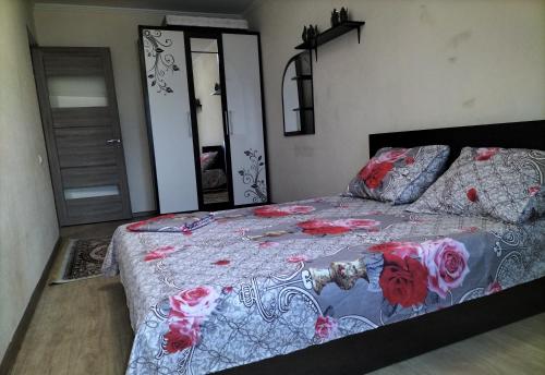 a bedroom with a bed with a floral bedspread at Квартира in Shymkent