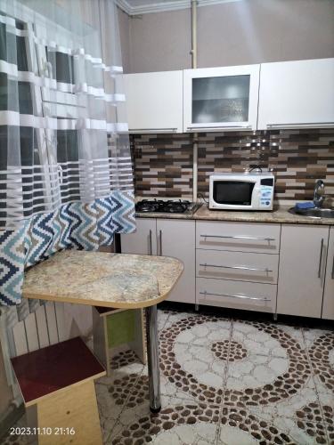 a kitchen with a table and a microwave at Квартира in Shymkent