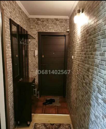 a hallway with a black door and a brick wall at Квартира in Shymkent