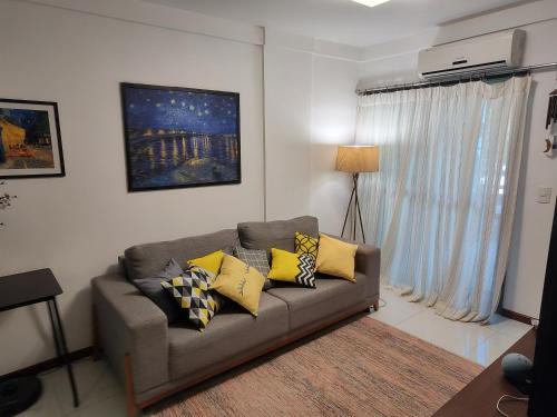 a living room with a gray couch with yellow pillows at Quarto e banheiro privativos com garagem fechada em apartamento aconchegante em Jardim da Penha in Vitória