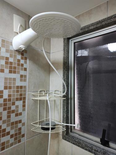 uma casa de banho com chuveiro e luz na parede em Quarto e banheiro privativos com garagem fechada em apartamento aconchegante em Jardim da Penha em Vitória