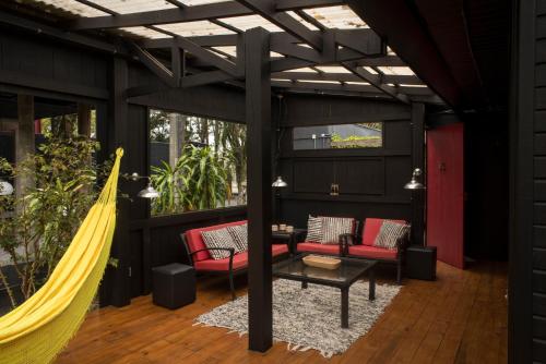 a patio with red chairs and a hammock at Pousada Vila do Mel in Pontal do Paraná