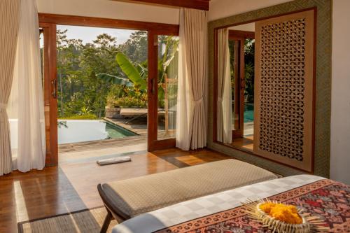 a bedroom with a bed and a view of a pool at Nau Villa Ubud in Tegalalang