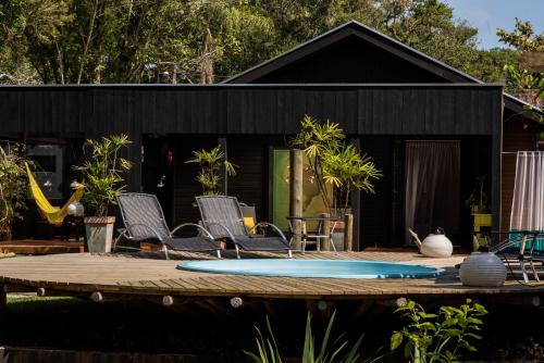 a black house with chairs and surfboards on a deck at Pousada Vila do Mel in Pontal do Paraná