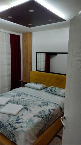 a bedroom with a bed with a yellow headboard at Apartman Luna in Valjevo