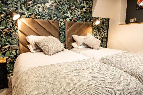 two beds in a hotel room with a wallpaper at VIP - 2 BR Grade 2 Luxury Industrial House with Log Burning FIRE & electric blinds in the Heart of the JQ in Birmingham