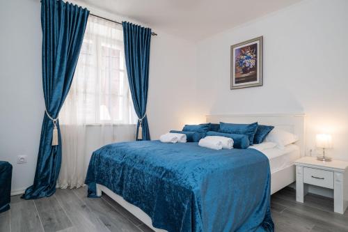 a bedroom with a bed with a blue blanket and a window at Rooms&Apartments Tomić in Ston