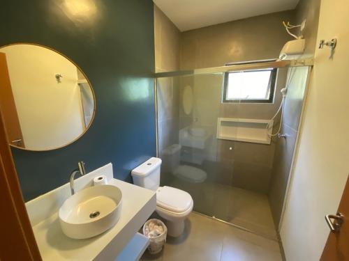 a bathroom with a sink and a toilet and a mirror at Paúba · Paúba Beach House -Em lindo condomínio c/ piscina in São Sebastião