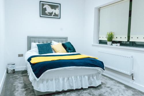 a white bedroom with a bed with blue and yellow pillows at Cosy 1Bed Apart with Wifi in Purley